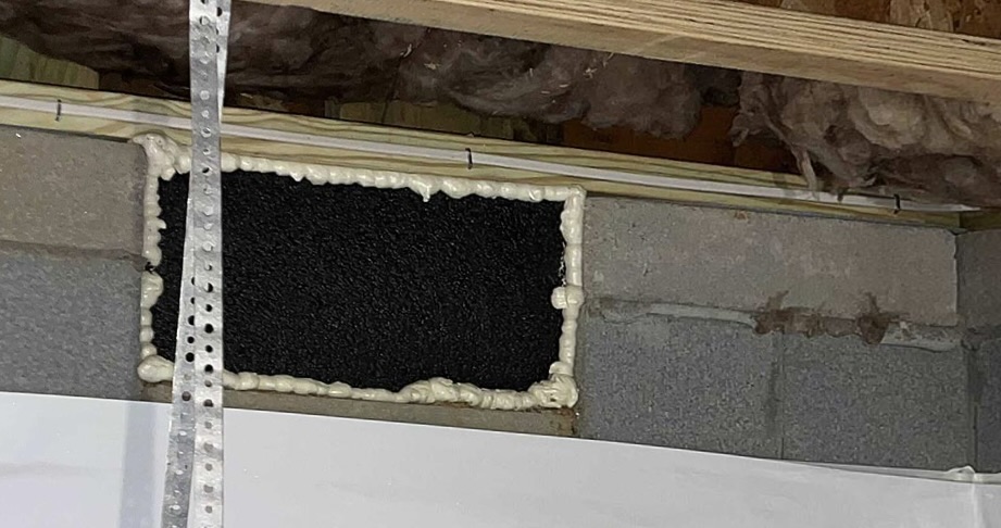 Technician sealing a foundation vent in crawlspace